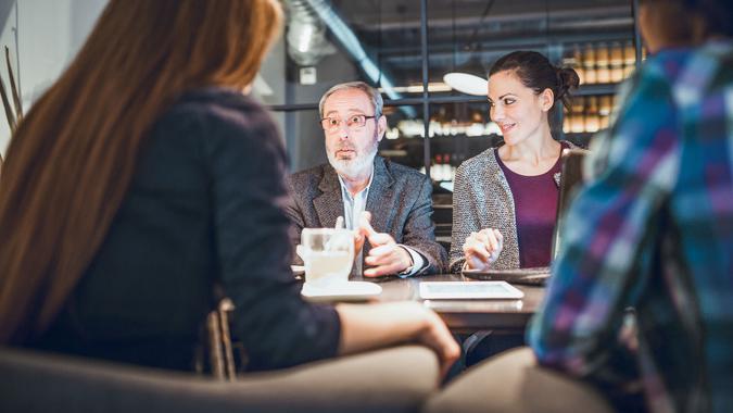 Senior businessman, creative team leader and his multi-ethnic, female team on the meeting in a high-end restaurant.