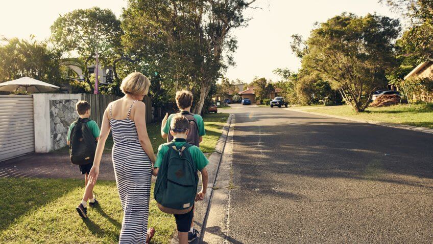 Shot of a mother walking three boys to school.