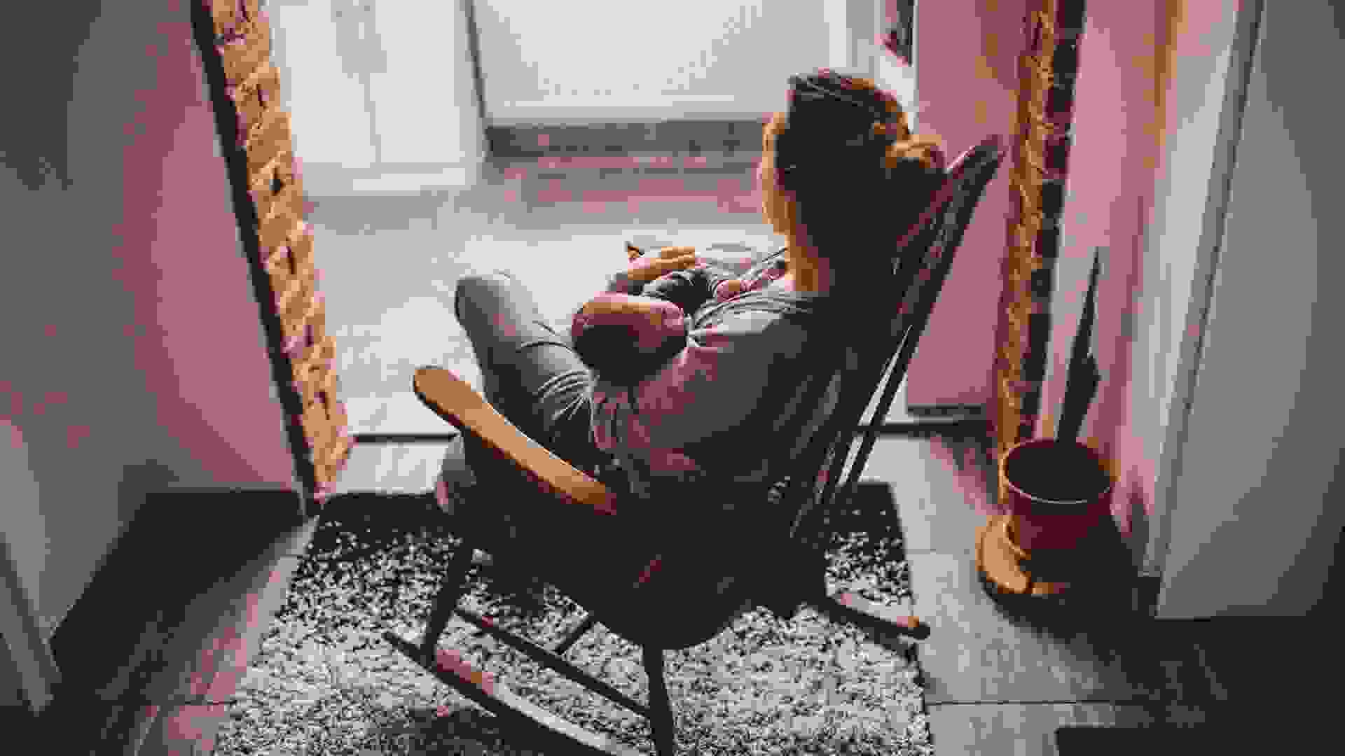 young mother holding her newborn baby, while sitting in a rocking chair.