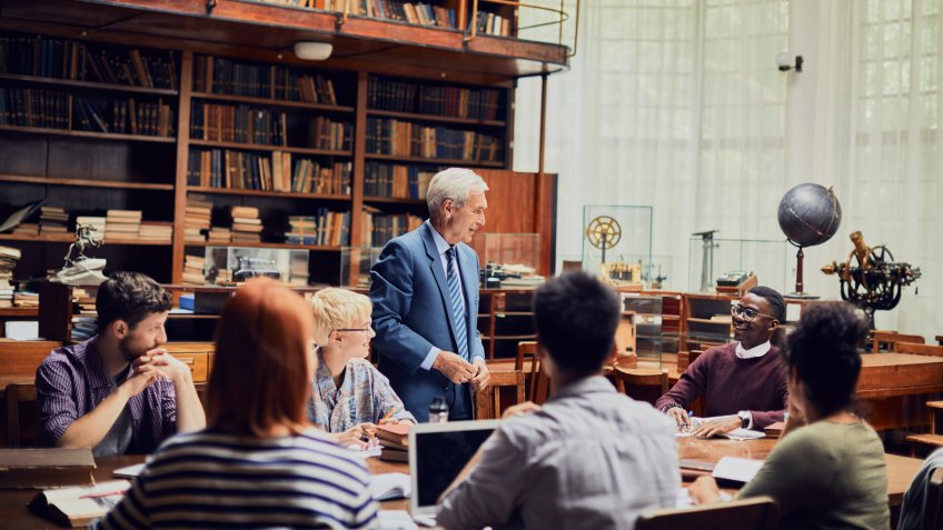 Close up of a group of students studying with their professor.