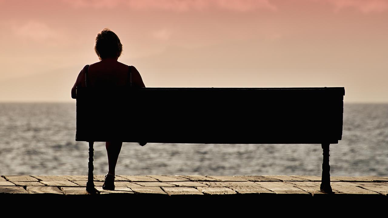 Silhouette of senior woman sitting alone on the bench in front of the sea - Image.