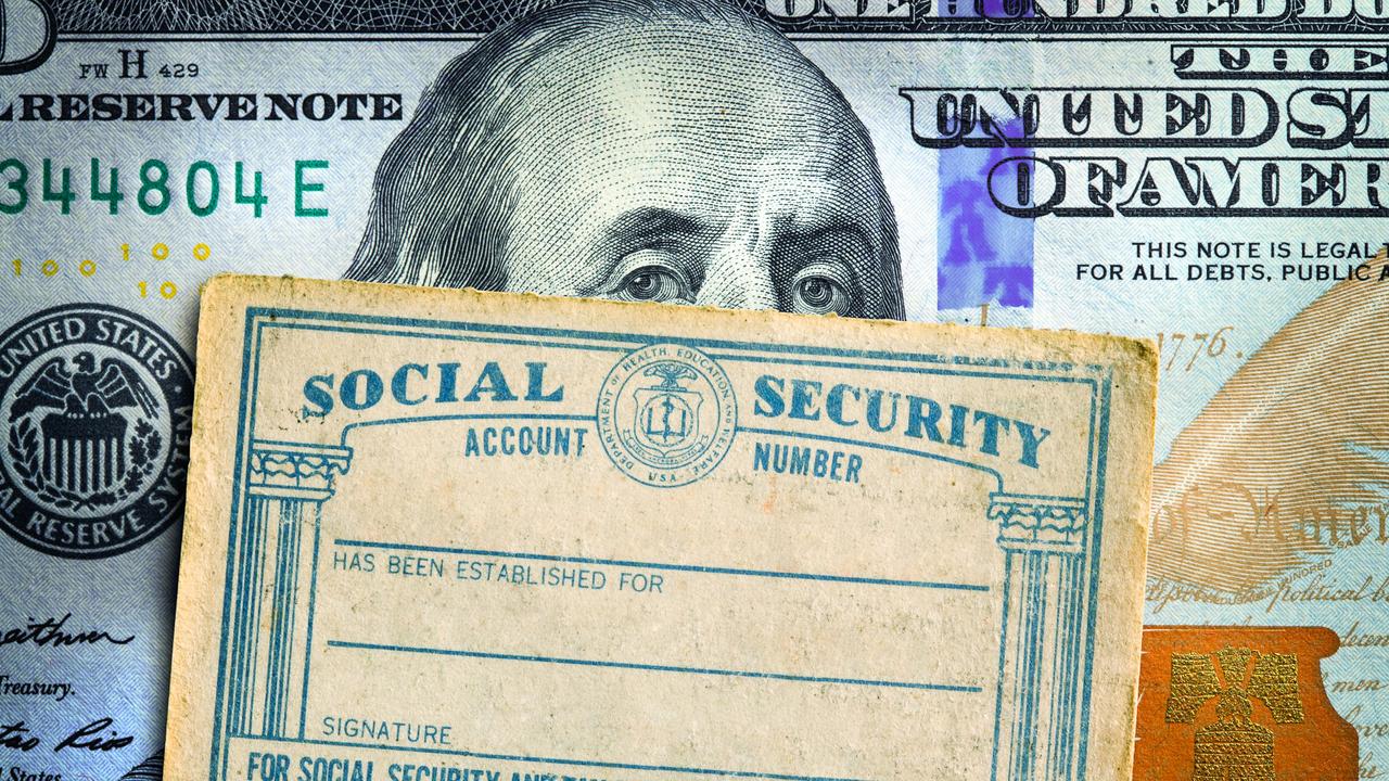 A Social Security card rests on top of a one hundred dollar bill.