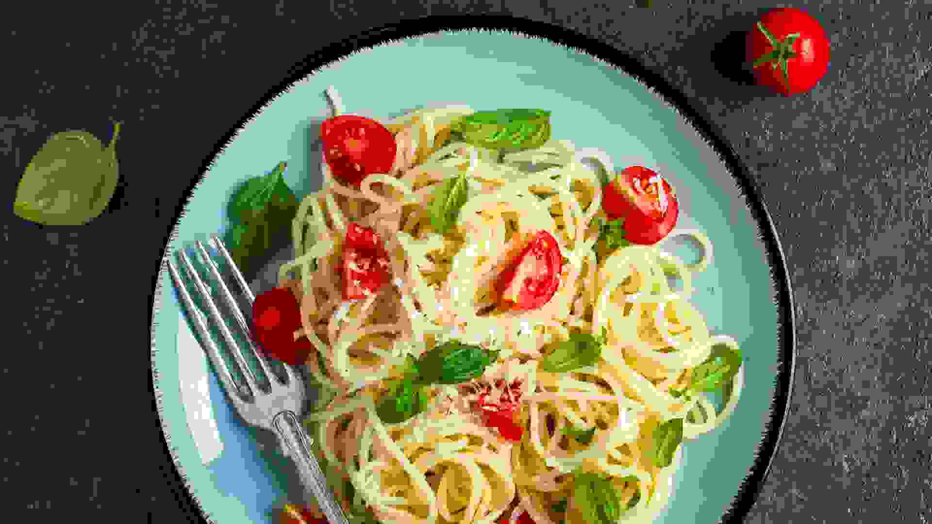 Spaghetti pasta with cherry tomatoes, basil and parmesan cheese, top view, copy space.