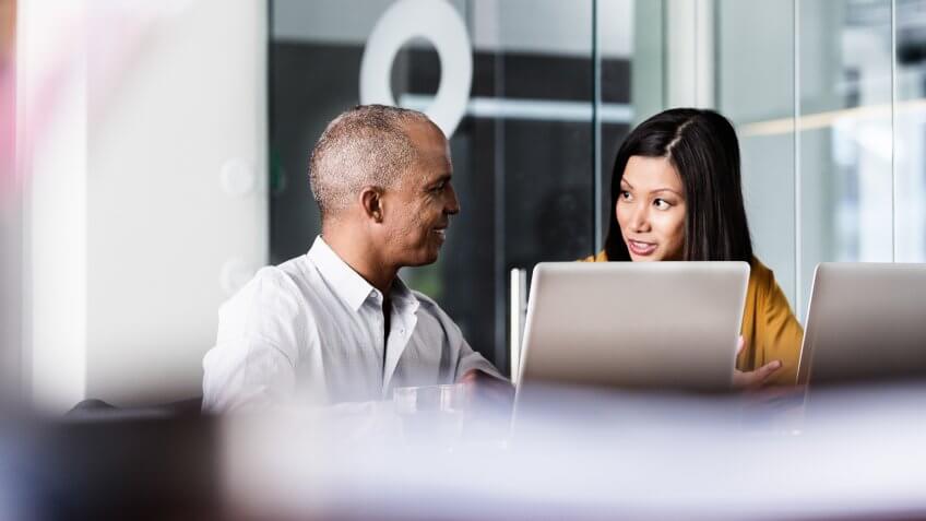 Multi-ethnic business people discussing at desk in office.
