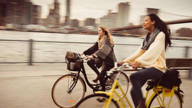 Two girl friends riding their bicycles along The East River in New York City.