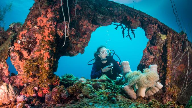 A female diver exploring the wreck Teshio Maru a Japanese Army Cargo Ship with 321 feet (98) on it's length, and was built in 1942-1944.