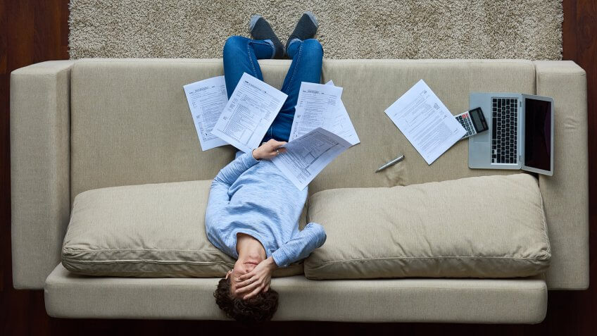 Failed woman leaning on sofa and covering face with hand, she holding business document.