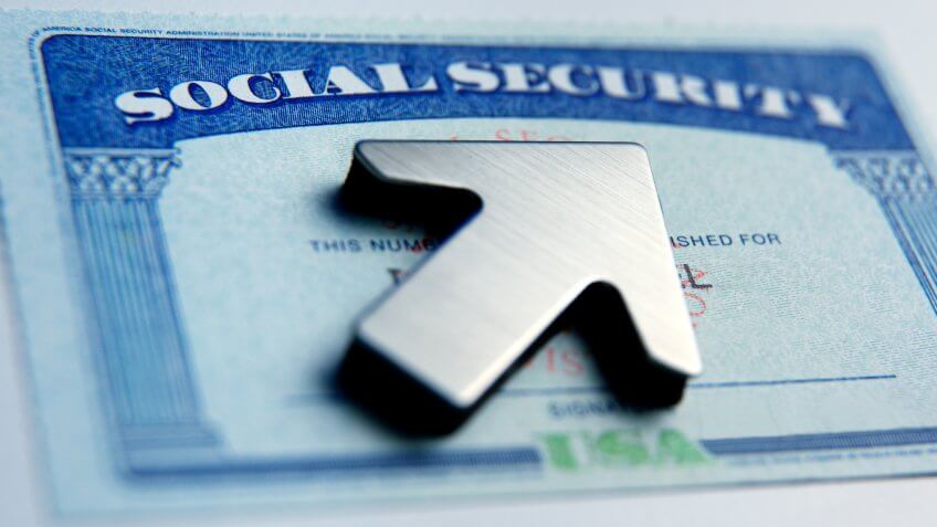 An upwardly pointing arrow rests on top of a social security card.