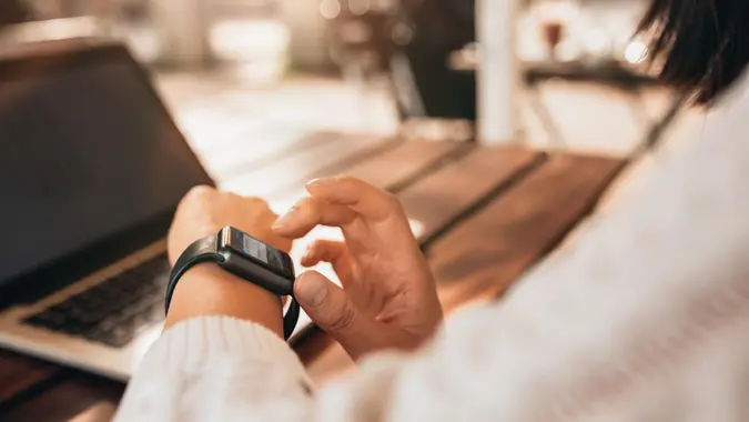 Close up of young woman using smartwatch at a cafe.