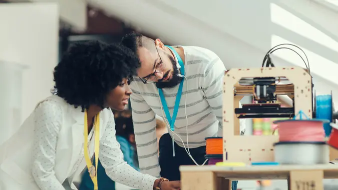 Creative Multi-Ethnic start-up business team working by 3D printer.