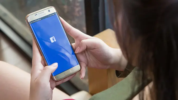 woman holding smartphone with Facebook app