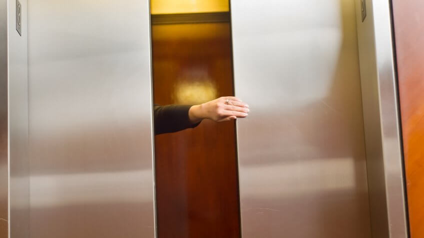 Woman's hand holding the elevator door.