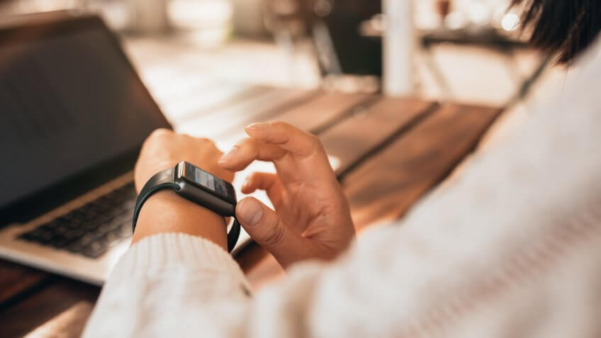 young woman using smartwatch at a cafe.