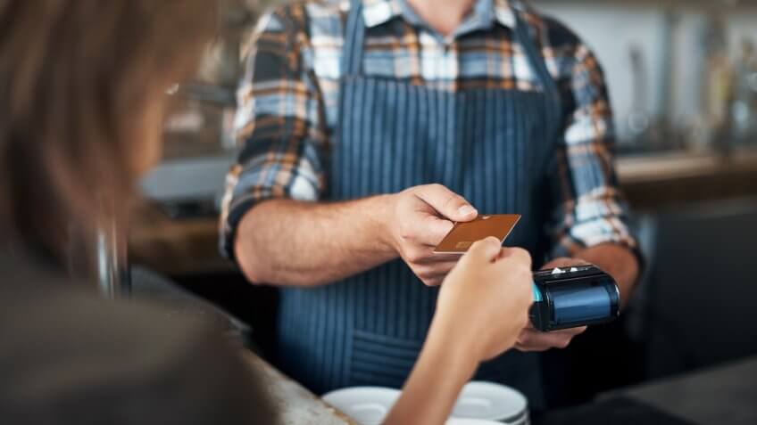Closeup shot of a unrecognizable person giving a barman a credit card as payment inside of a restaurant.