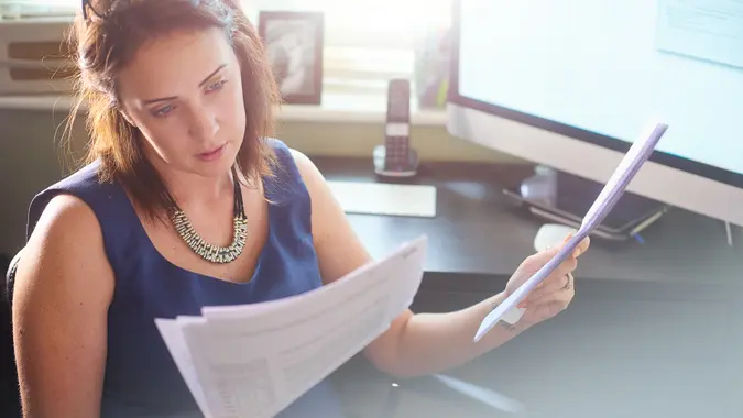 A businesswoman sits at her desk reading through paperwork.