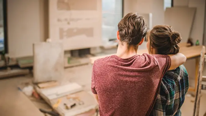 Rear view of loving couple standing embraced in their apartment that is renovating.