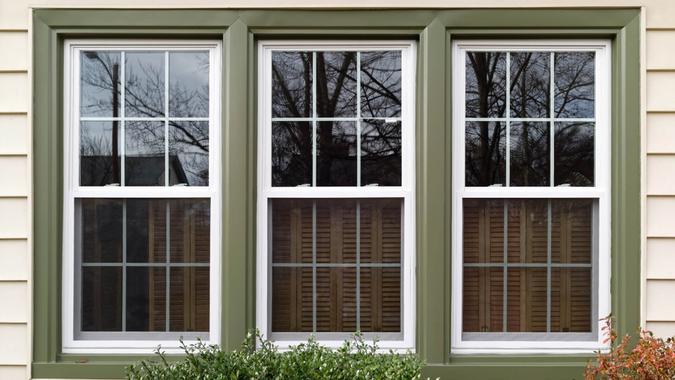 Three new replacement windows with green trim on front of house.