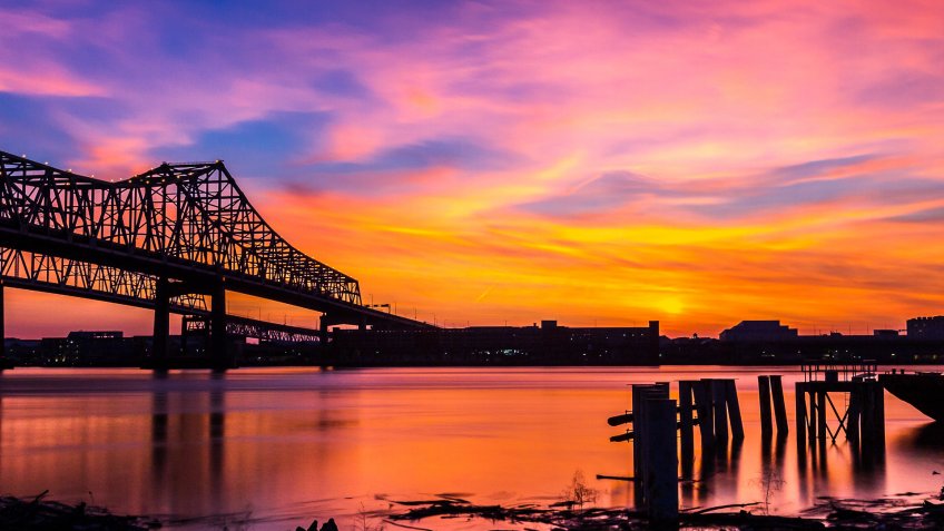 Silhouette of the Crescent City Connection and the City of New Orleans, USA over the Mississippi River during Sunset.