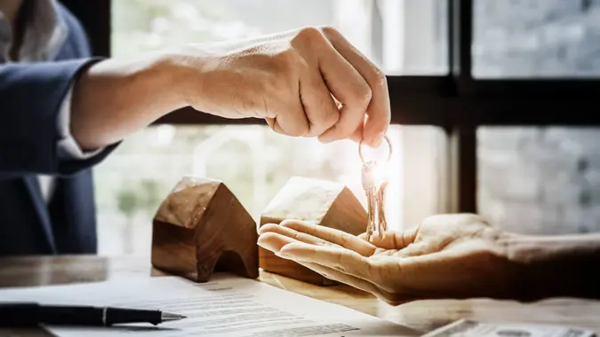 estate agent giving house keys  of customer  and holding dollar us bank at  agency office.