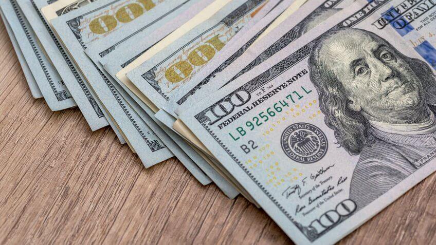 american dollar bills on wooden desk.