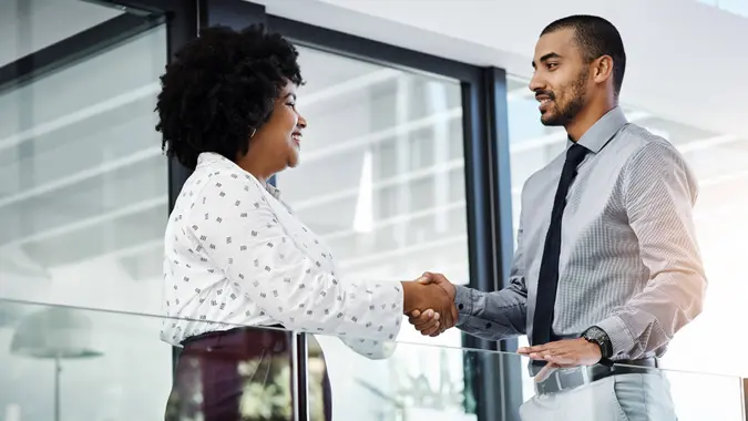 Shot of a businessman and businesswoman shaking hands in a modern office.