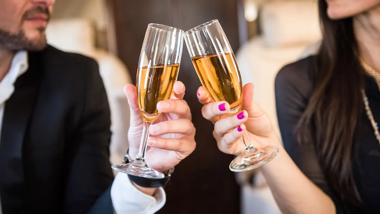 champagne glasses that business couple is holding inside the private jet aeroplane.