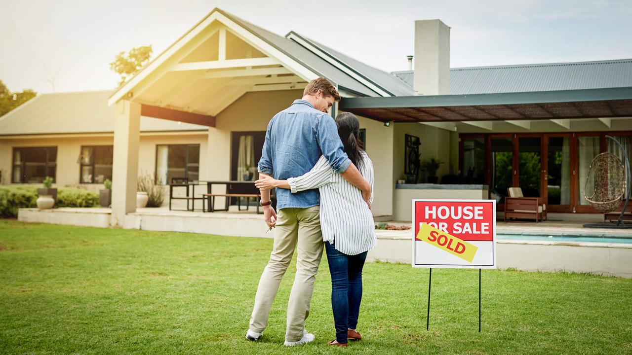 couple admiring their new house with mortgage rates dropping