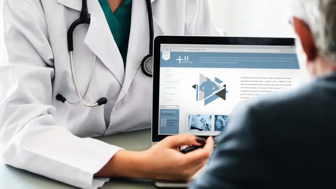doctor pointing out information on laptop to patient