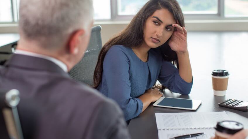 Business leader instructing focused Indian female assistant.