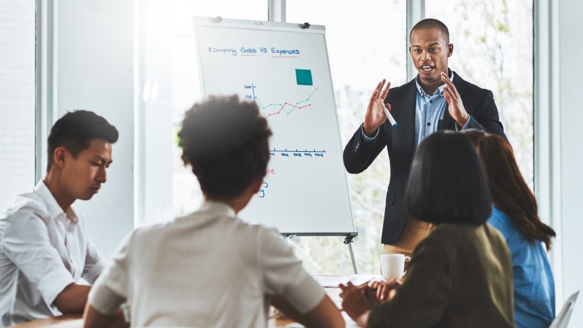 Shot of a young businessman delivering a presentation to his team in a modern office.