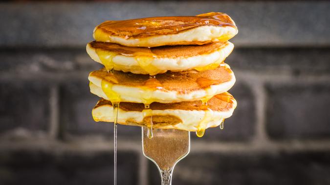 fork holding short stack of pancakes with syrup dripping for National Pancake Day