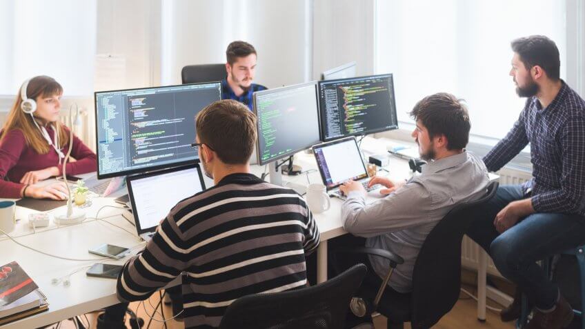 Group of software developers sitting at desktop computers being focused on their work.