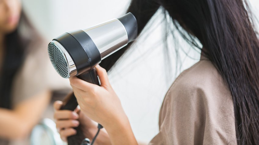Woman with a hair dryer to heat the hair.
