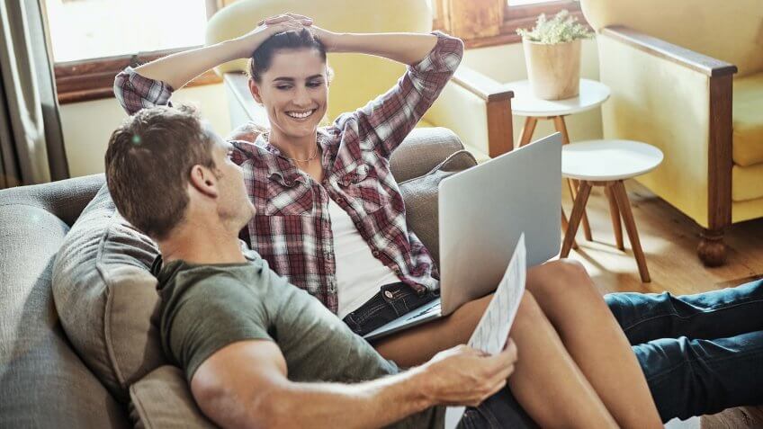 Shot of a couple using a laptop while going through paperwork at home.
