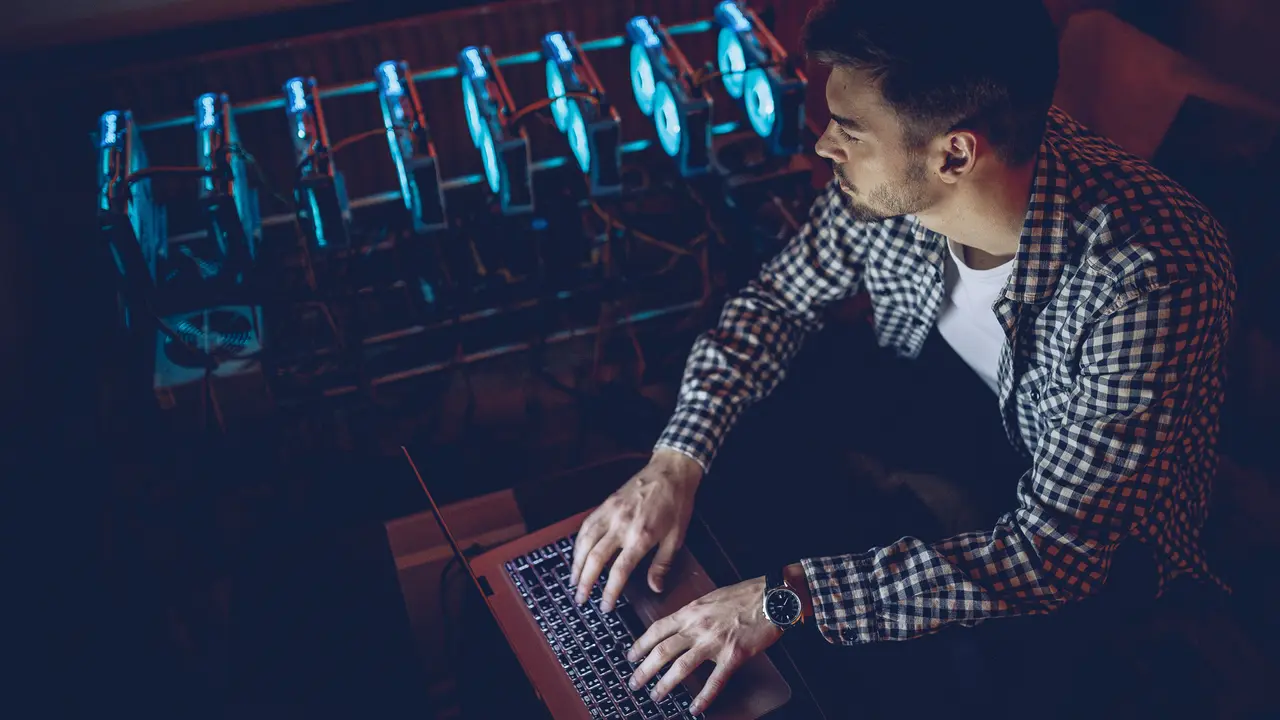 One man, sitting in his office next to the mining rig, using computer for mining bitcoin.