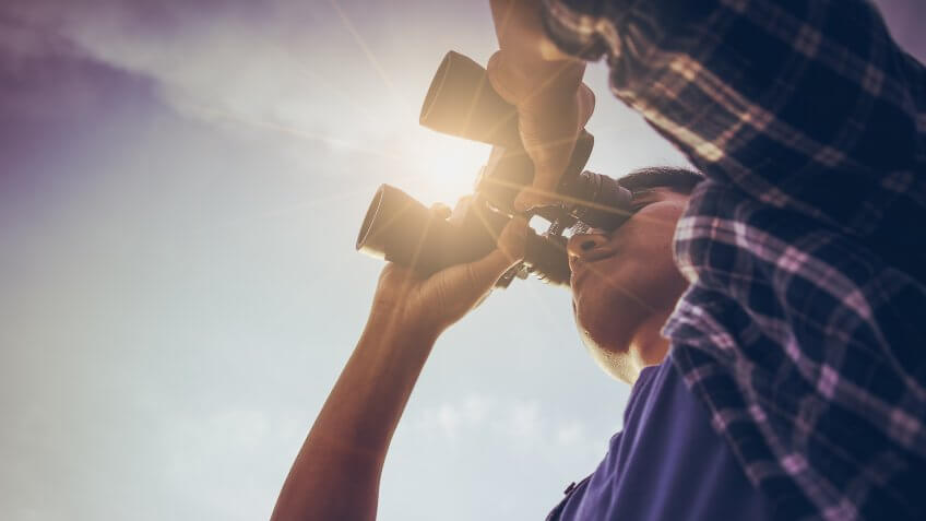 man using binoculars to look in the distance