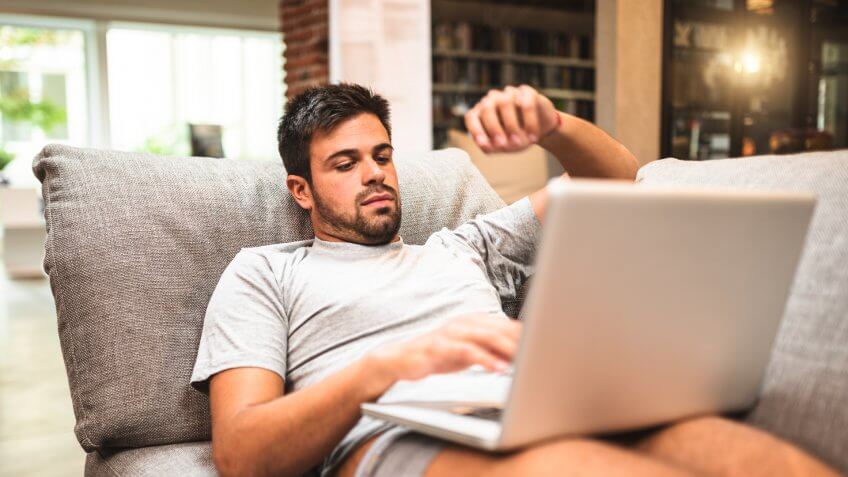 30s, Adult, Break, Caucasian, Close-up, Comfortable, Computer, Domestic Life, E-Mail, Home Interior, Human Hand, Indoors, Internet, Laptop, Latin American and Hispanic Ethnicity, Lifestyles, Lying Down, Male, Male Beauty, Men, Mobility, Netbook, One Person, PC, Pajamas, Relaxation, Resting, Serious, Sitting, Sofa, Surfing the Net, Technology, Using Computer, Using Laptop, Wireless Technology, Working, Working At Home, Young Adult, casual, living room, people