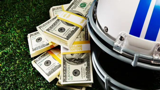 American football helmet next to a pile of money.