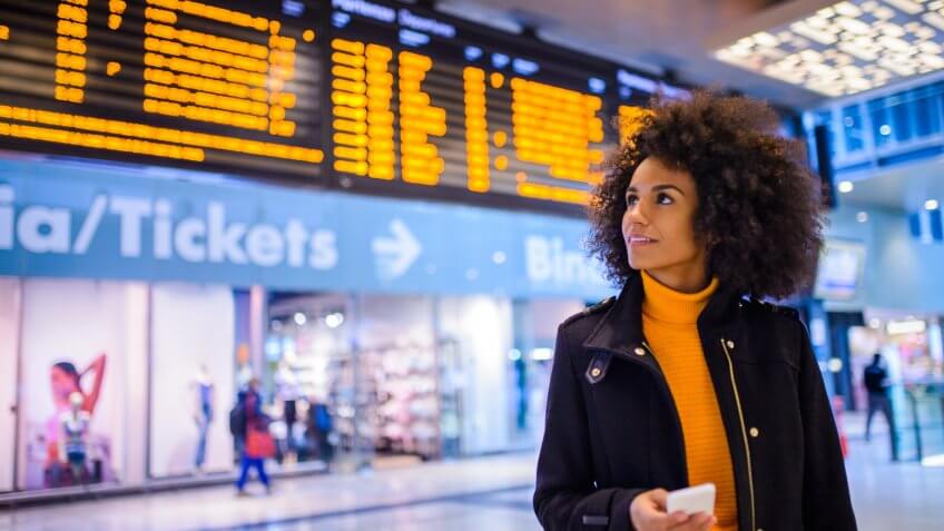 Smiling woman using mobile phone at the airport.