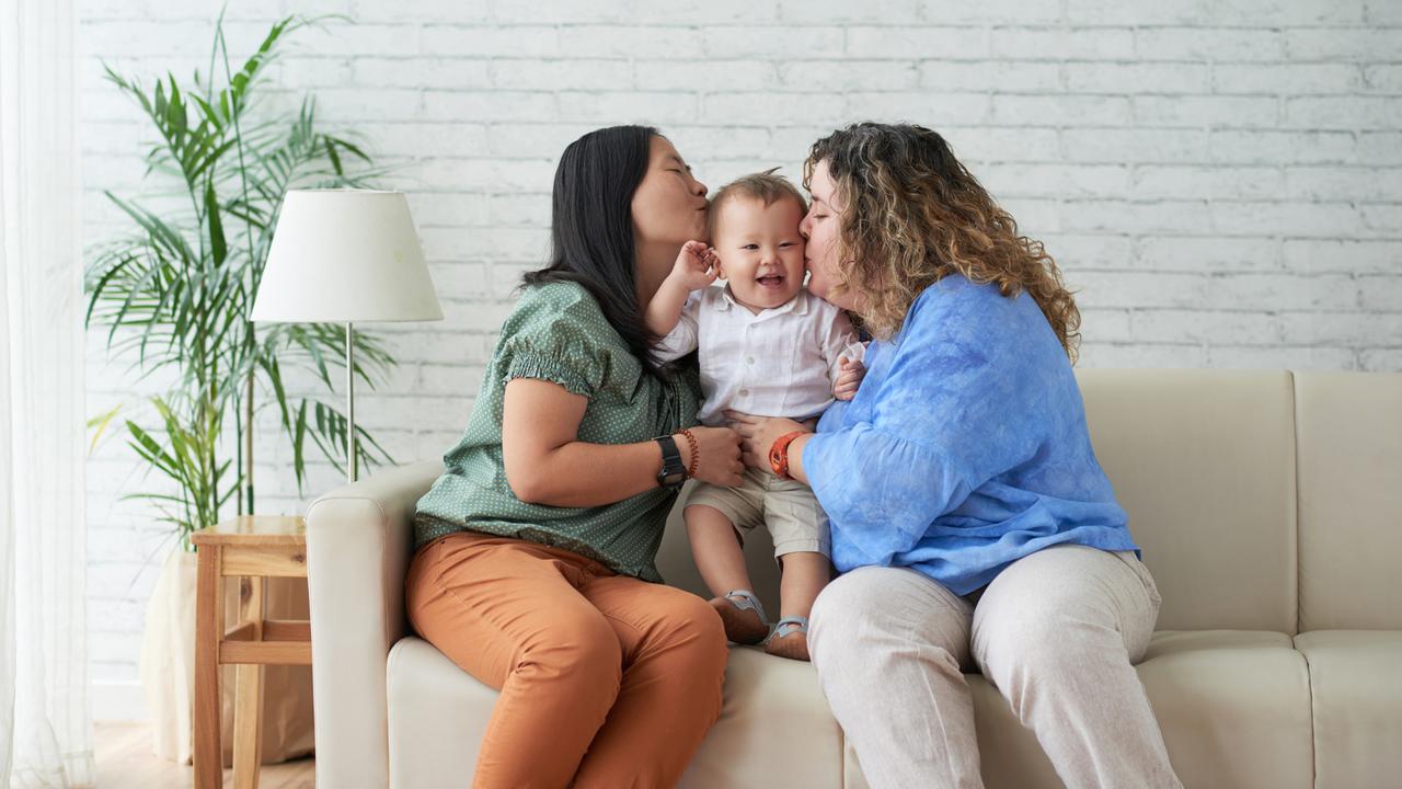 Mothers kissing their happy laughing child on both cheecks.