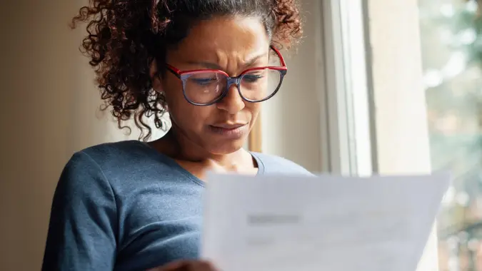 Portrait of worried black woman standing beside window.