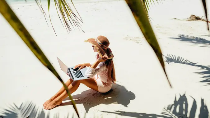 freelancer woman with laptop on beach.