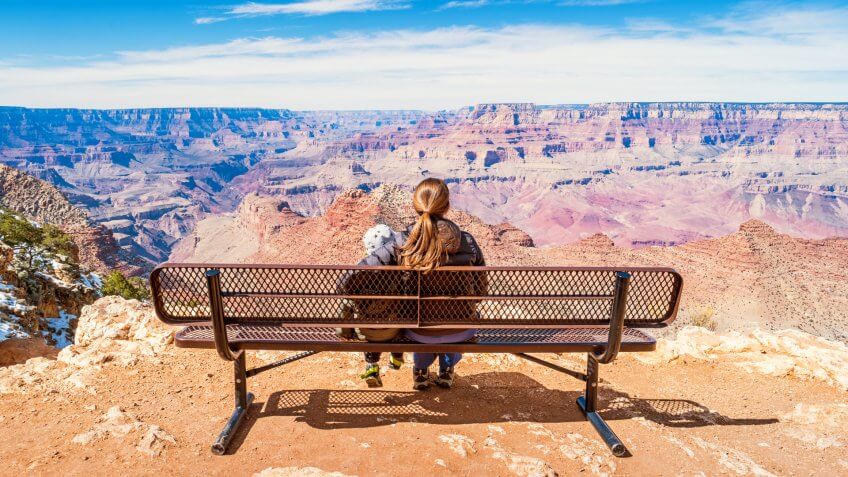 Stock photograph of a mother with child looking at view in Grand Canyon National Park, South Rim, USA on a sunny day.
