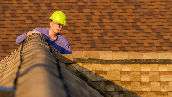 Home inspector examines architectural, asphalt shingled roof. An inspector looks over a residential roof at the peak.