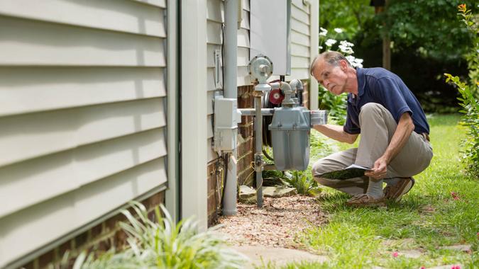 An inspector examines a residential gas meter and associated piping.