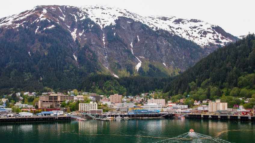 A ship's tender cruising into the port at Juneau, Alaska with snow covered mountains in background.