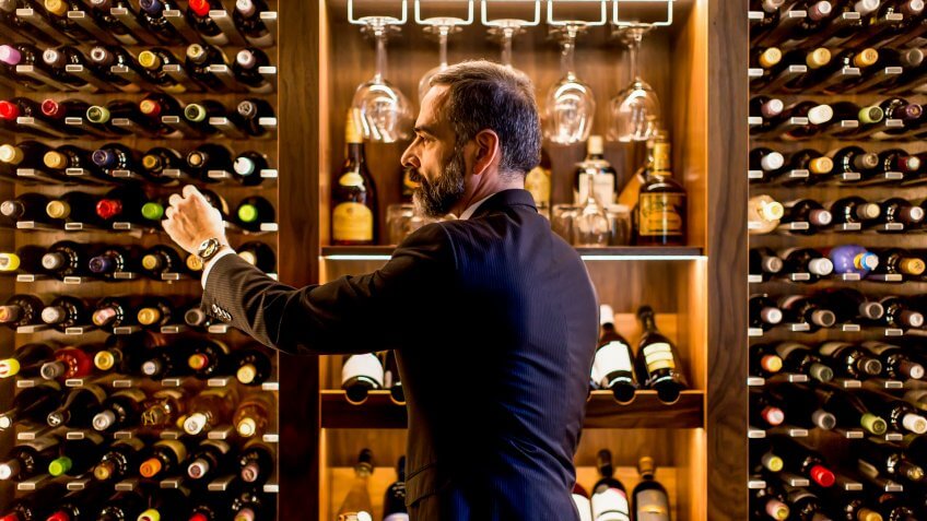 Middle-aged handsome man chooses a bottle of wine.