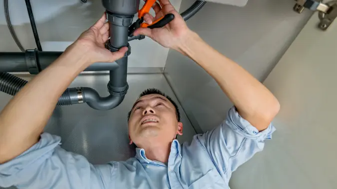 Man repairing sink pipe in the kitchen.