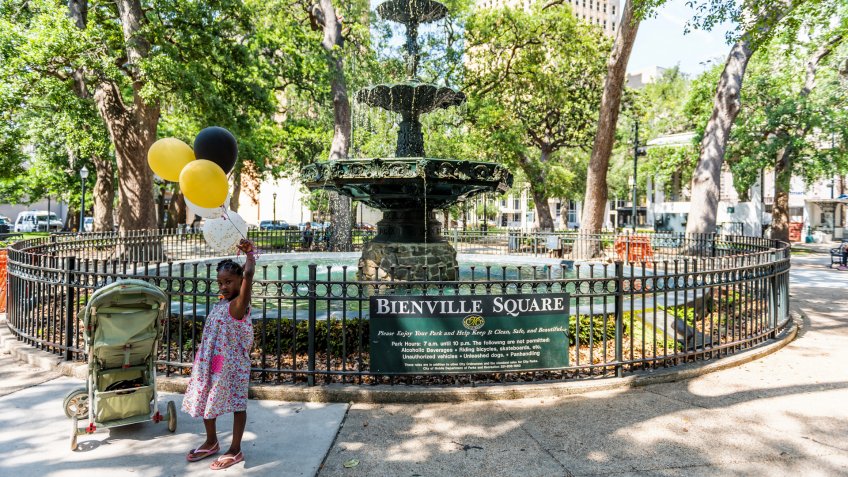 Mobile, USA - April 22, 2018: Old town Bienville square fountain in park by street in Alabama famous southern town, city, young african american girl with balloons.