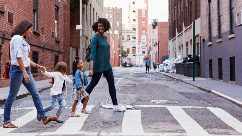Two mother friends with two daughters crossing the road.
